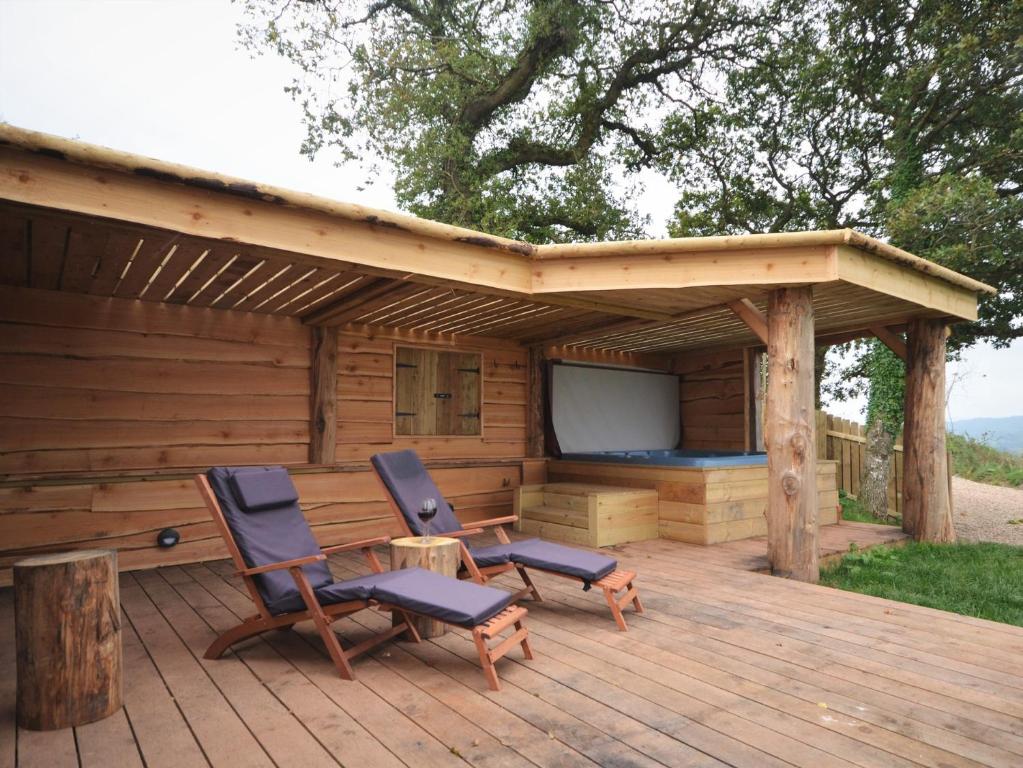 a deck with two chairs and a television on a cabin at 1 Bed in Bickleigh 53296 in Cadeleigh