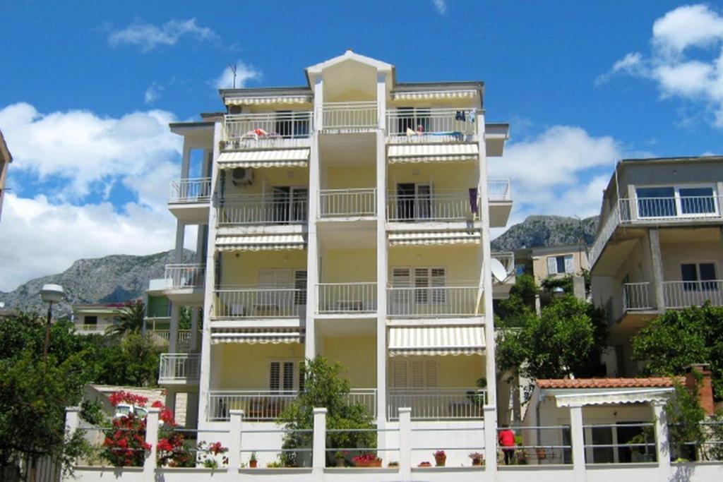 a tall yellow building with white balconies at Apartments by the sea Podgora, Makarska - 2615 in Podgora