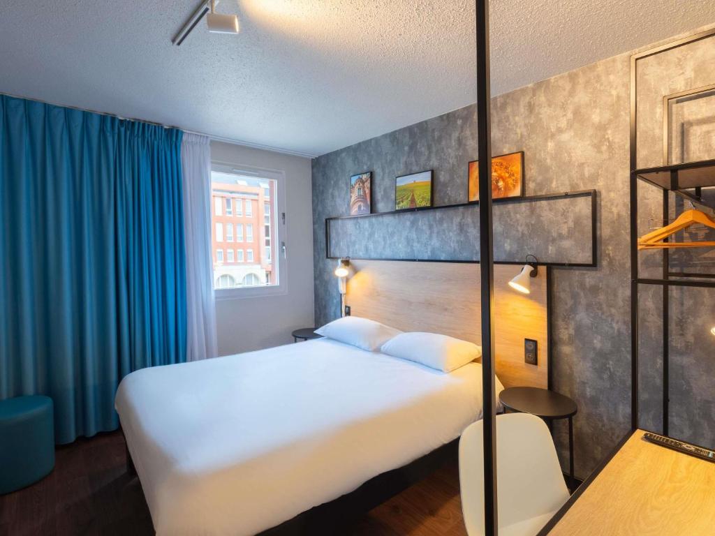 a hotel room with a bed and blue curtains at ibis Epernay Centre Ville in Épernay