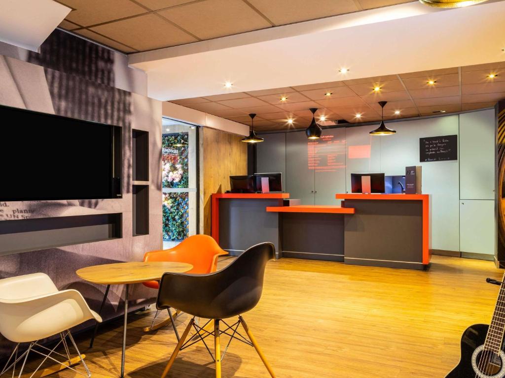a room with a table and chairs and a tv at ibis Paris Gare du Nord La Fayette in Paris