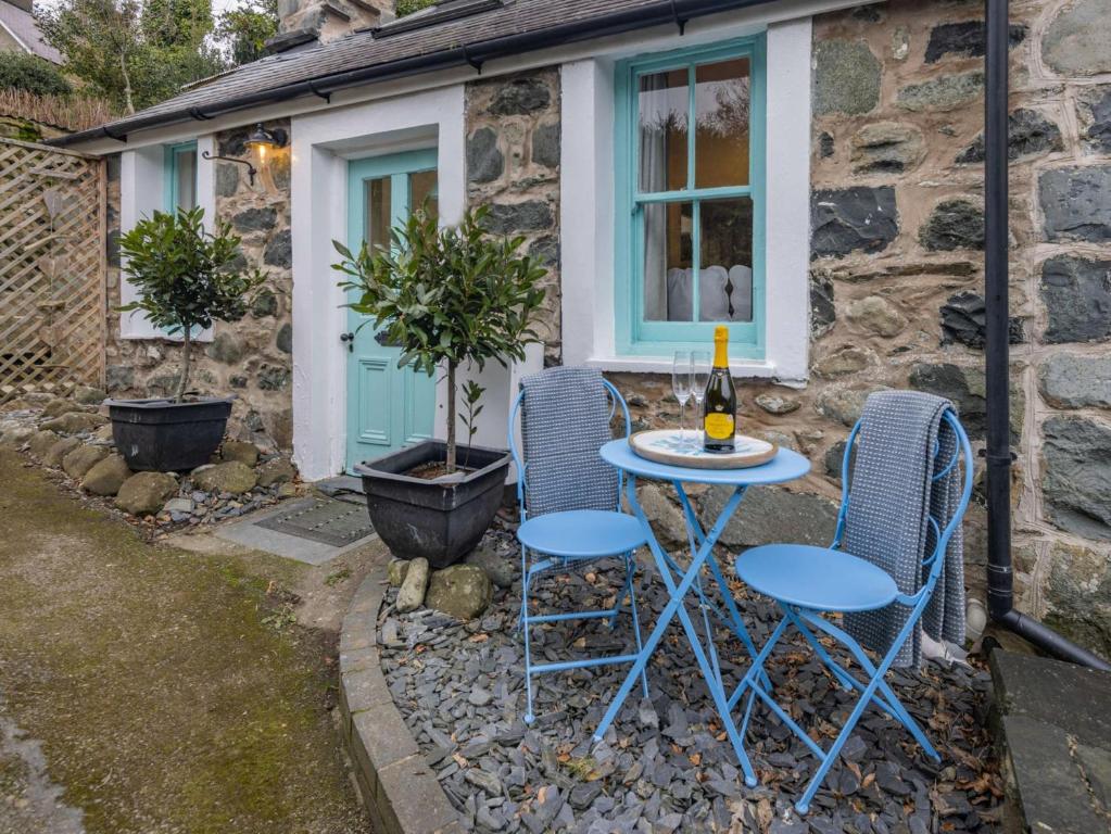 un tavolo e sedie di fronte a un cottage in pietra di 2 Bed in Llwyngwril 58564 a Llwyngwril