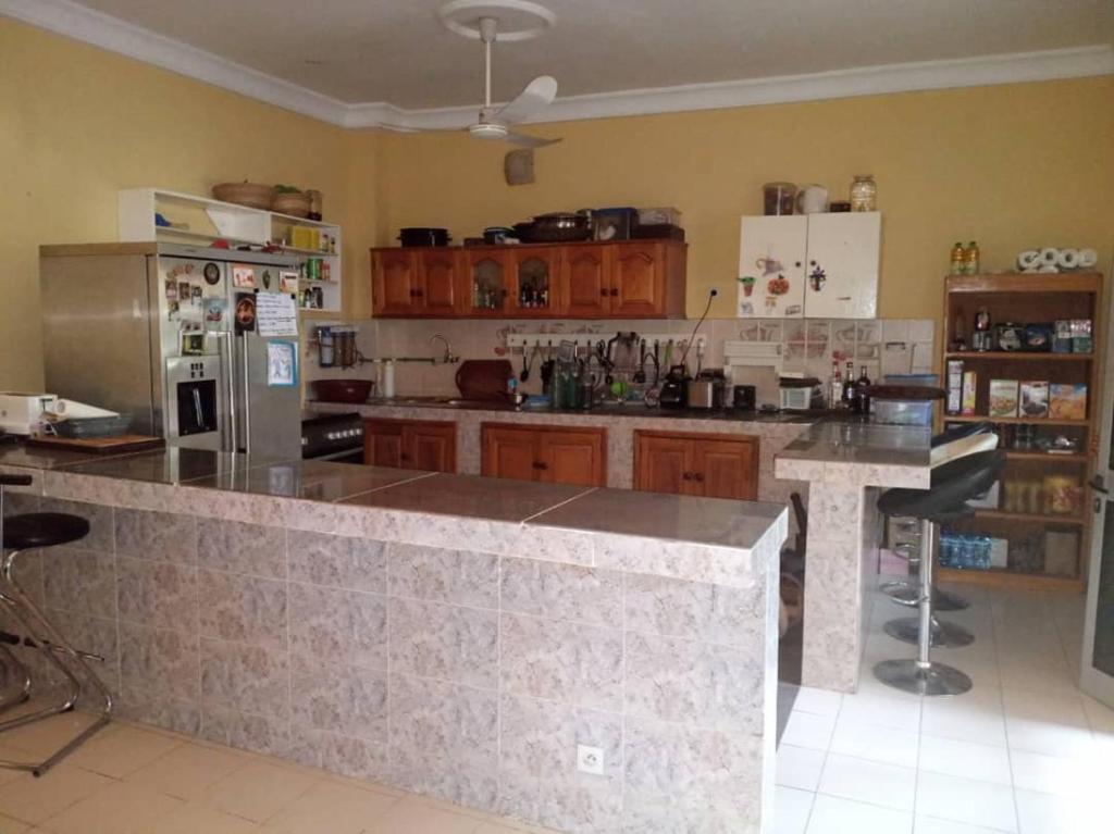 a large kitchen with a counter and a refrigerator at La Villa sûr in Niamey