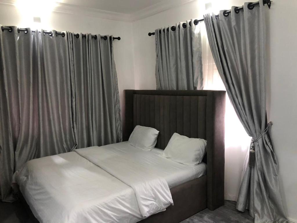 a bed in a bedroom with curtains and a window at Cozystay in Abuja