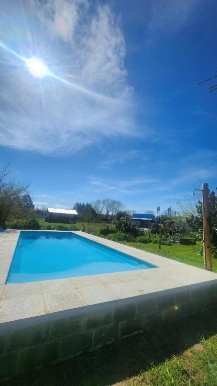 a large blue swimming pool with the sun in the sky at Casa Aguaribay- Lomas Altas- in Chascomús