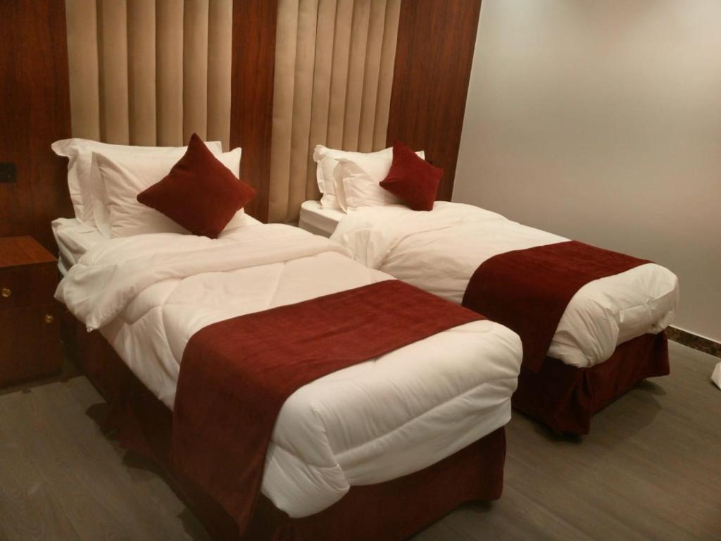 two beds in a hotel room with white and red at الجوهرة بارك 1 in Riyadh