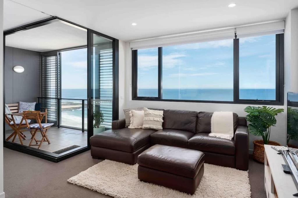a living room with a leather couch and glass windows at 806 - Beachfront Beauty - Prices Slashed Until Dec 2025 in Newcastle