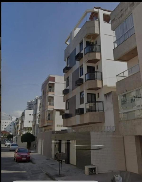 a tall building with a car parked in front of it at Apartamento Praia do Morro in Guarapari