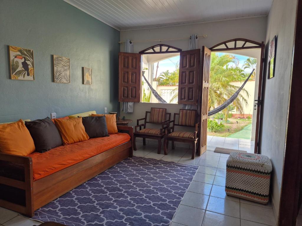 a living room with an orange couch and an open door at CASA DA PRAÇA Ibicoara - a melhor hospedagem in Ibicoara