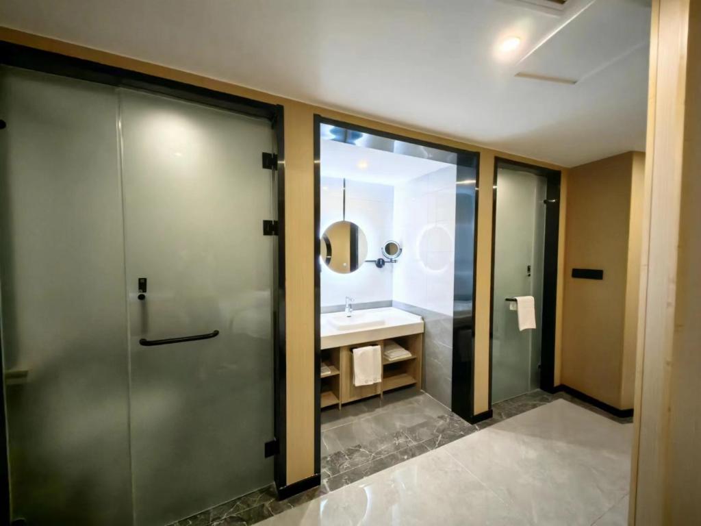 Un baño con lavabo y ducha de cristal. en Floral Hotel Qingdao Dreamship Seaview Hotel, en Qingdao