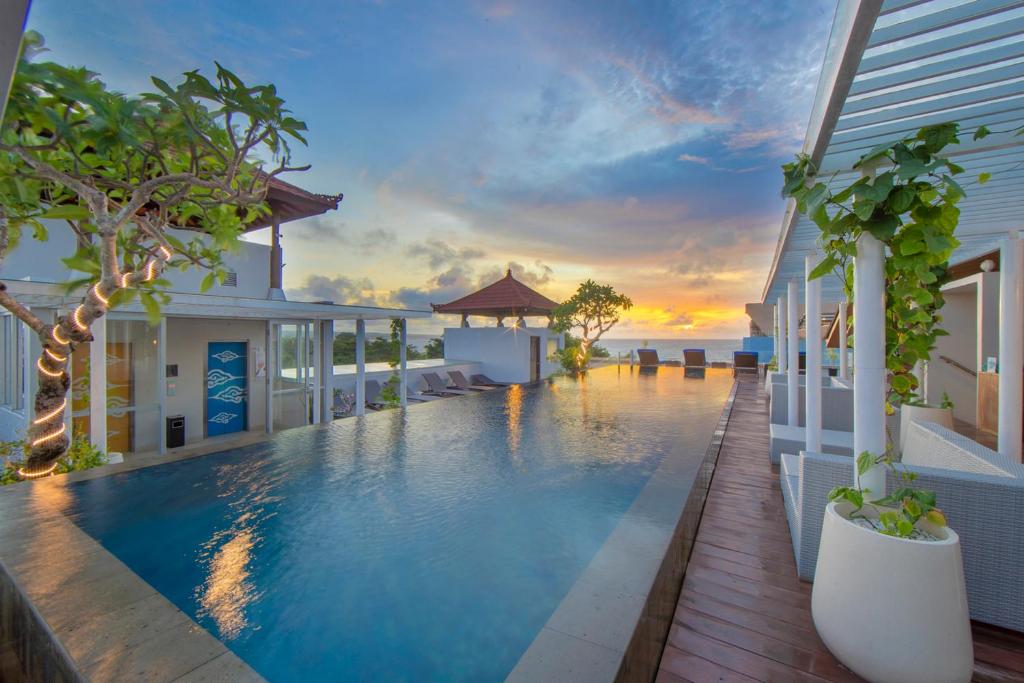 a swimming pool in front of a building with a sunset at Kuta Beach Hotel in Kuta