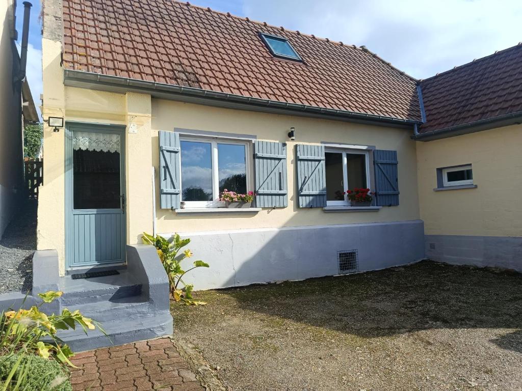 ein gelbes Haus mit zwei Fenstern, in denen Blumen stehen in der Unterkunft Le chant des grenouilles in Boismont