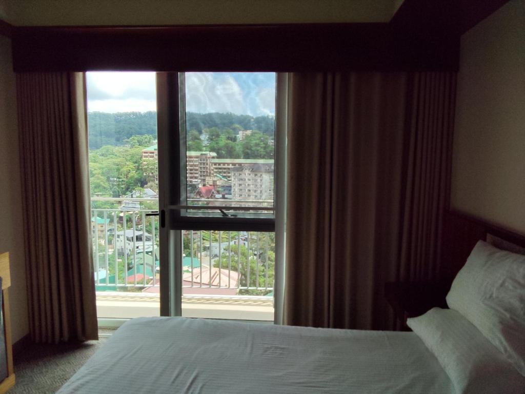 una camera d'albergo con un letto e una grande finestra di Studio 510 A Slice of Baguio Paradise with pool and view a Baguio