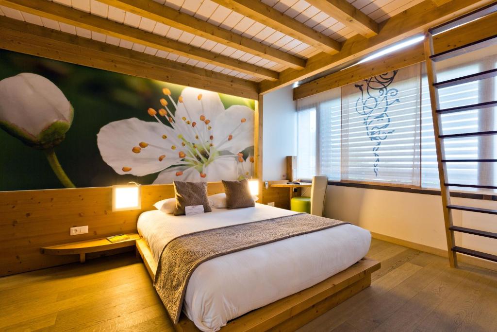 - une chambre avec un grand lit orné d'une peinture florale sur le mur dans l'établissement La Croix de Savoie & Spa, aux Carroz d'Arâches