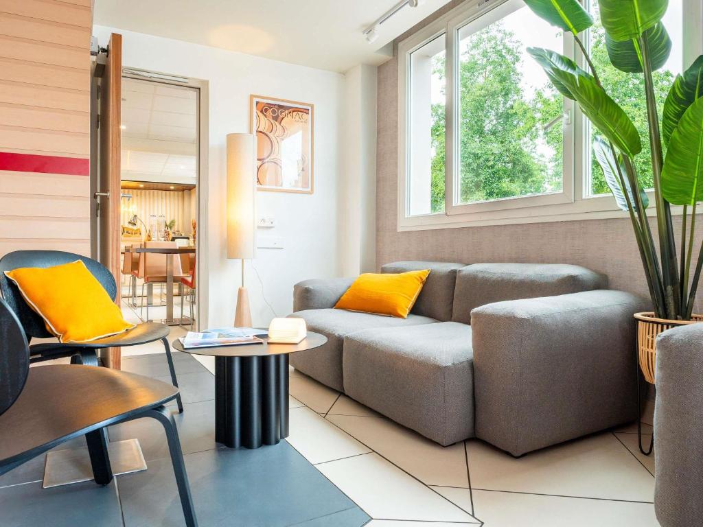 una sala de estar con un sofá y una mesa en Hôtel Ibis Cognac Centre, en Cognac