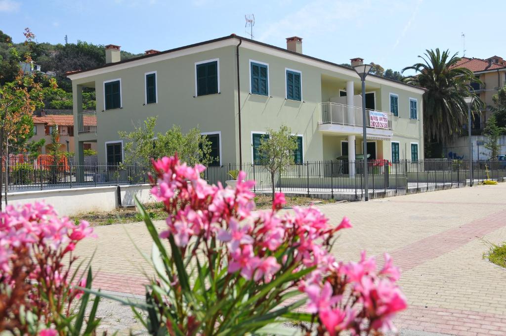 Um edifício com flores cor-de-rosa à frente. em Villaggio La Piana em Cervo