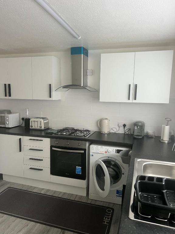 a kitchen with a stove and a washing machine at The Cosy Haven - 2 Bedroom house in Manchester