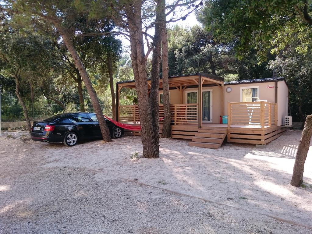 een klein huisje met een auto ervoor geparkeerd bij Auto kamp Cuka in Pakoštane