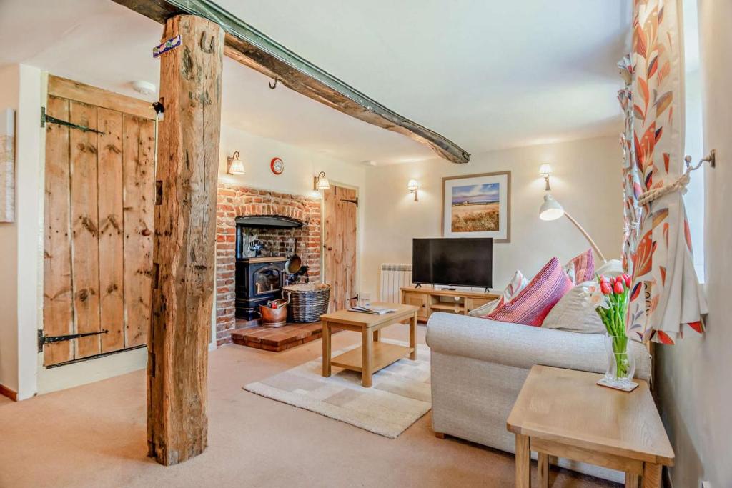 un salon avec un canapé et une télévision dans l'établissement Bourne Cottage, à Weybourne