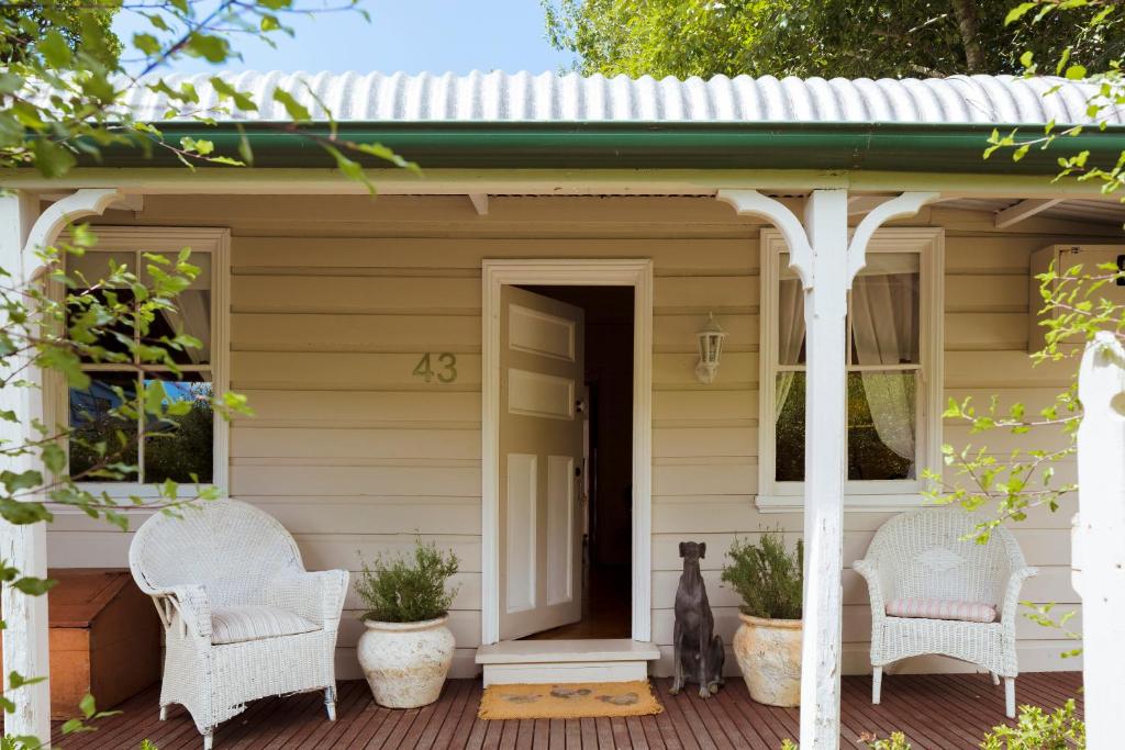 a porch of a house with white wicker chairs at Illalangi Boutique Cottage in Blackheath