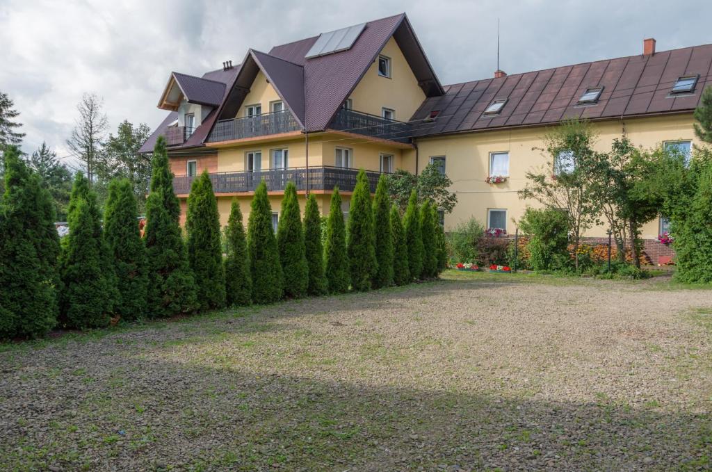 a house with a row of trees in front of it at Ośrodek wypoczynkowy "Jak u Mamy" in Mszana Dolna