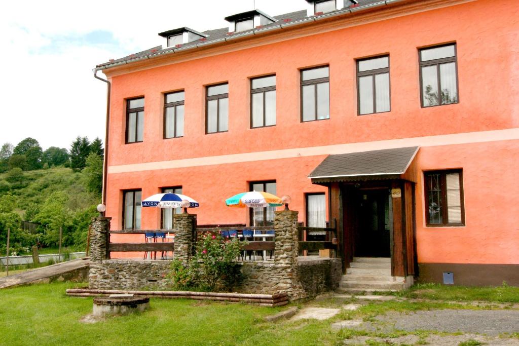 a building with tables and umbrellas in front of it at Penzion Muflon in Bělá nad Radbuzou