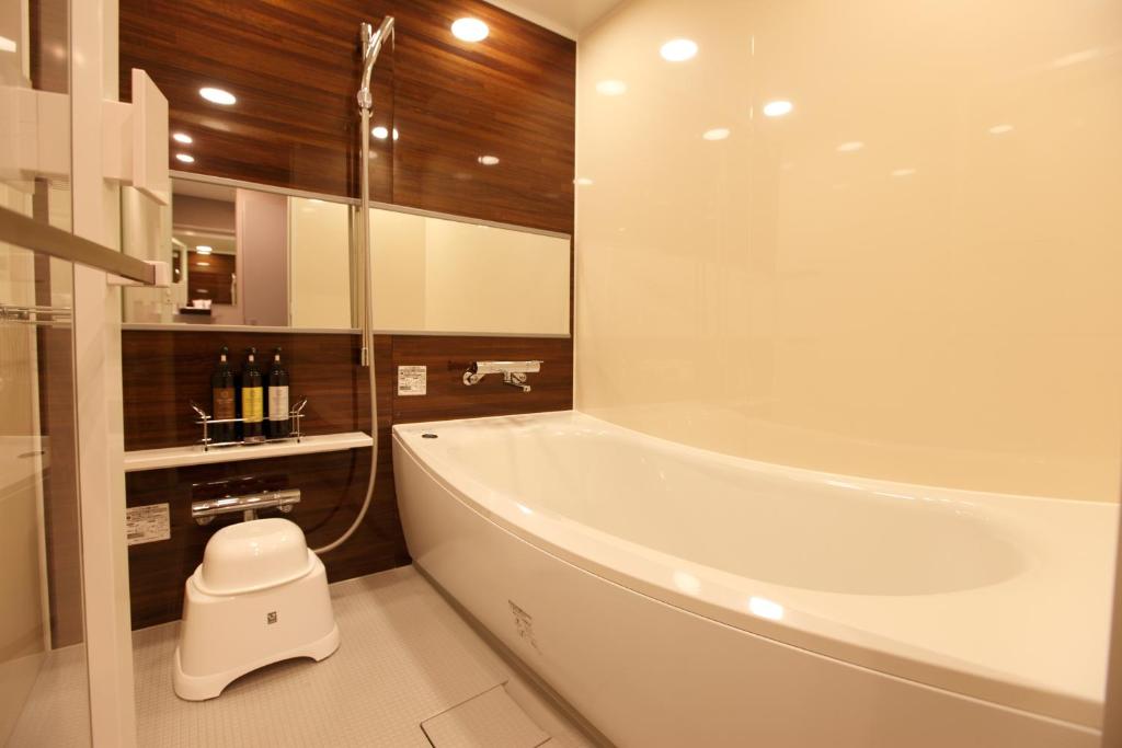 a bath tub sitting next to a toilet in a bathroom at Hotel Amanek Ginza East in Tokyo