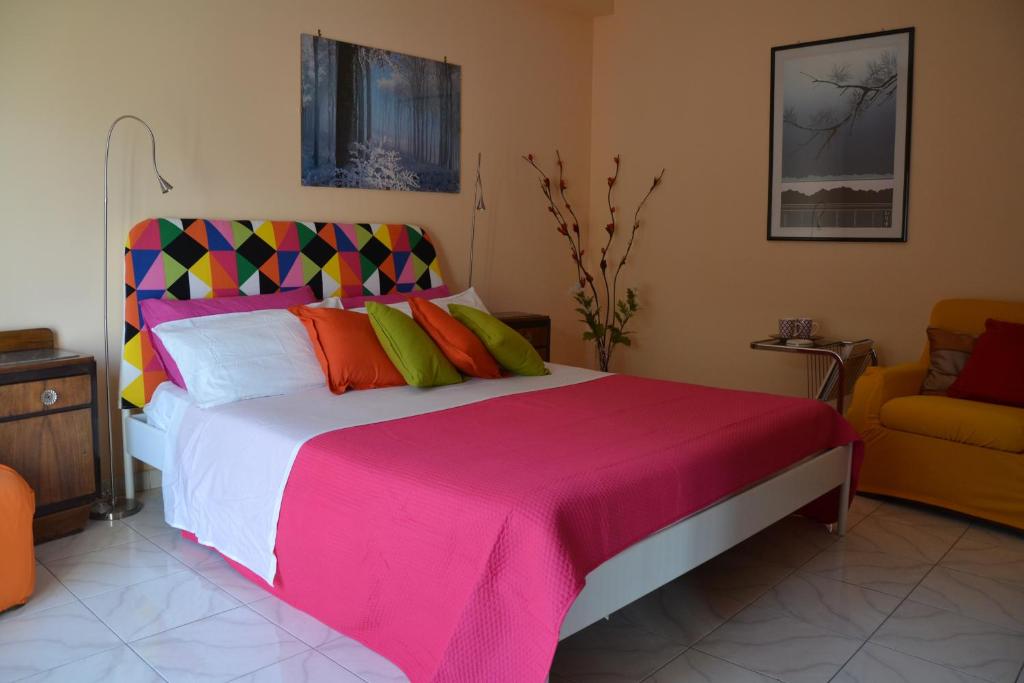 a bedroom with a large bed and a yellow chair at Holiday House Etna Mare Taormina in Mascali