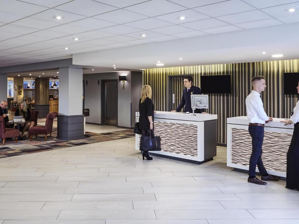 a group of people standing at a counter in a lobby at Novotel Wolverhampton City Centre in Wolverhampton