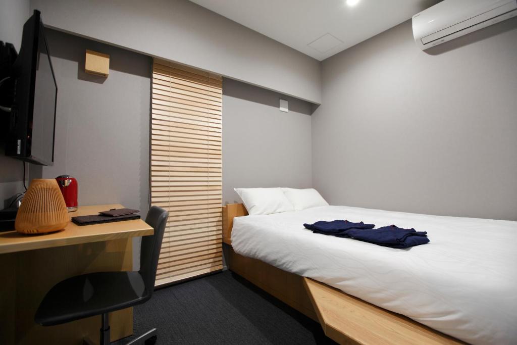 HOTEL AMANEK Ginza East في طوكيو: غرفة نوم مع سرير ومكتب مع جهاز كمبيوتر