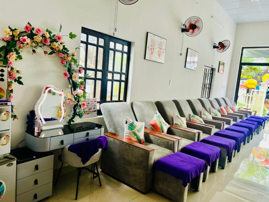 un salon avec une rangée de chaises grises avec des coussins violets dans l'établissement NET Spa & Massage Hoi An, à Thanh Ðông (1)