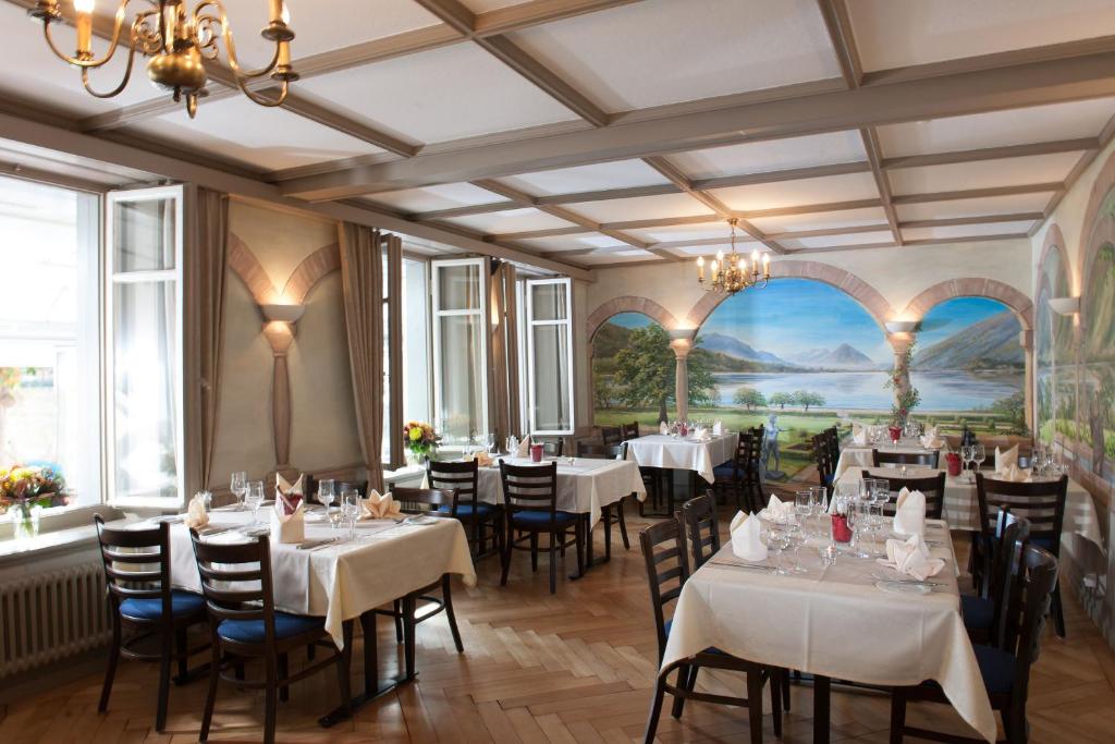 un restaurante con mesas y sillas blancas y una pintura en la pared en Jungfrau Hotel, en Wilderswil