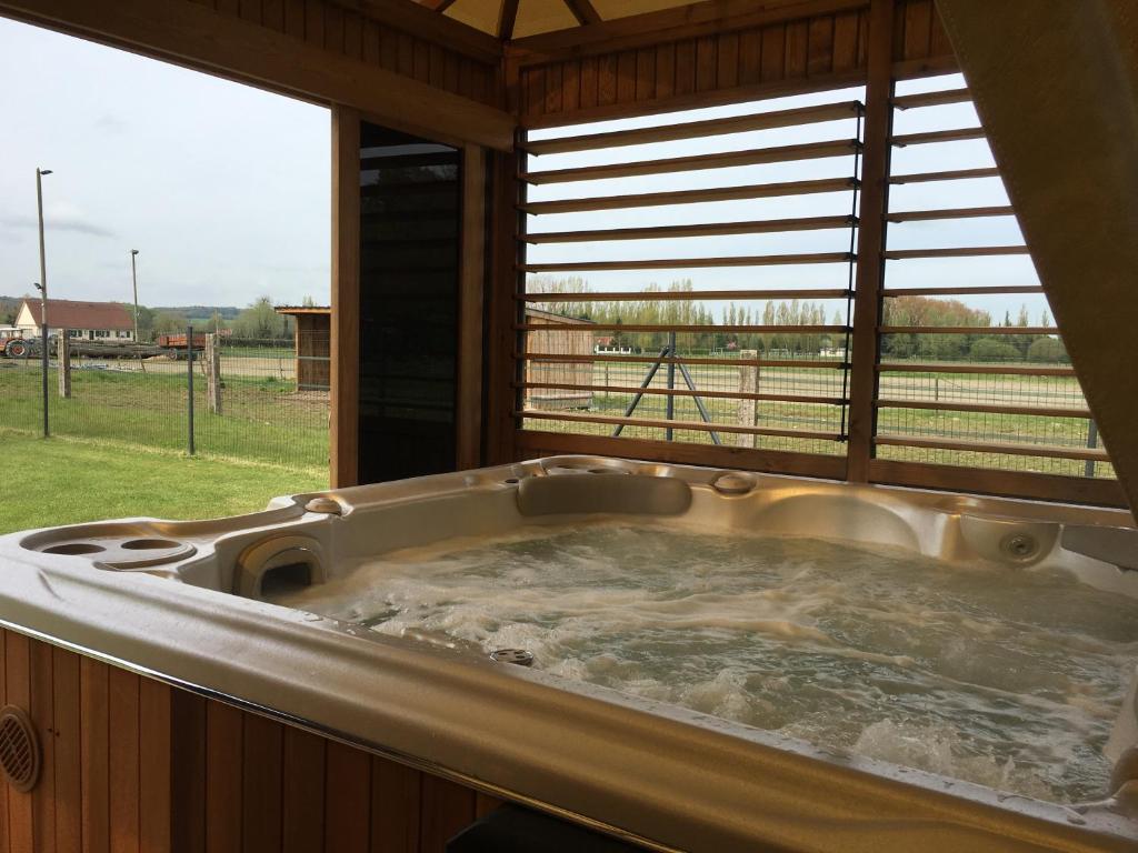 a hot tub in a room with a view of a field at Les Portes de la baie in Grand-Laviers