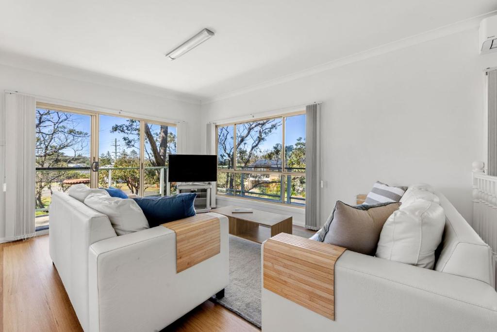 a living room with two white couches and a tv at Ocean Echoes - Pet Friendly with Ocean Glimpses in Culburra Beach