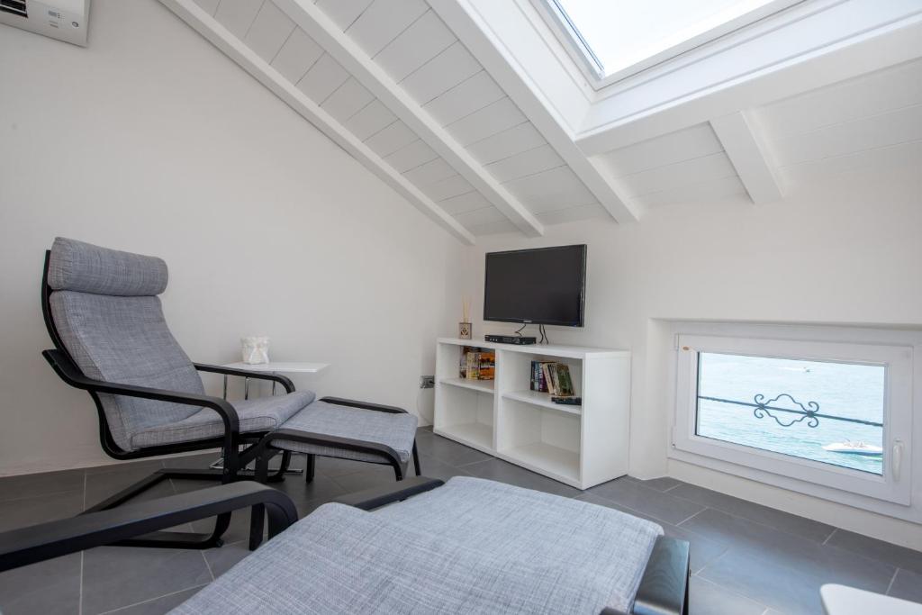 a white living room with a chair and a window at Il Pontile in Bellagio