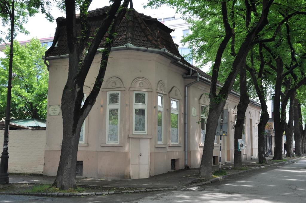 a building on the side of a street with trees at Guest House Best Food in Subotica
