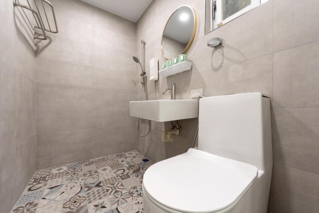 ein Badezimmer mit Toilette, Waschbecken und Spiegel in der Unterkunft 暮樂行旅 -改裝新登場-預訂後務必連絡民宿再一次確認 in Anping