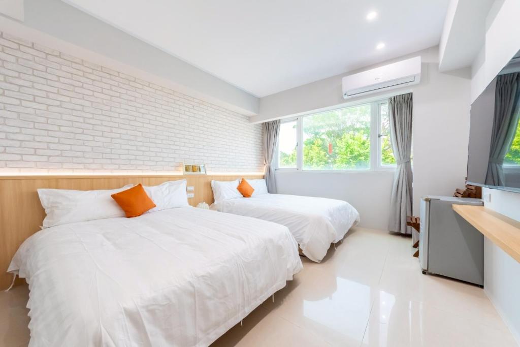 Dos camas en una habitación con televisión y ventana. en 暮樂行旅 -改裝新登場-預訂後務必連絡民宿再一次確認, en Tainan