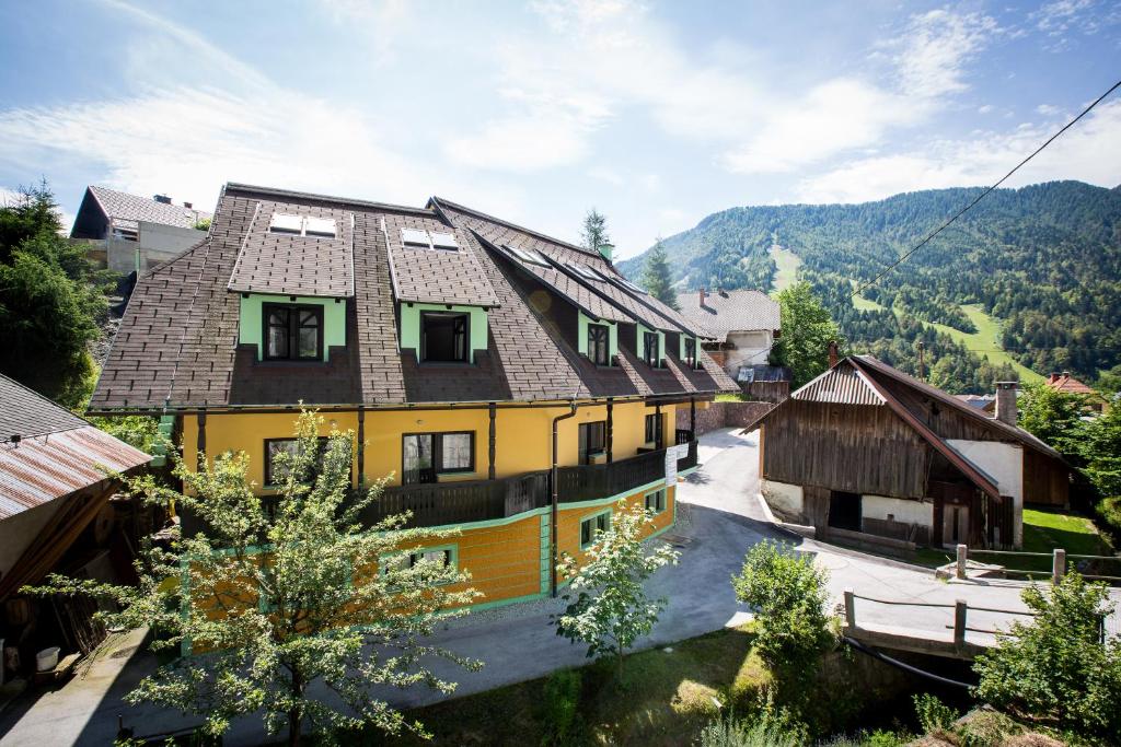 een geel huis met een bruin dak bij Podkoren Apartments in Kranjska Gora
