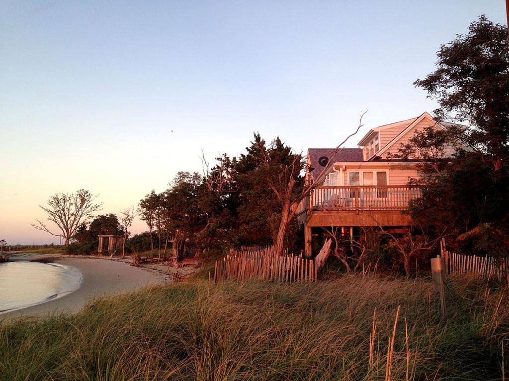 une maison au bord d'une plage avec une clôture dans l'établissement Bayfront Cottage Rental with a Private Beach on Virginia's Eastern Shore, à Onancock