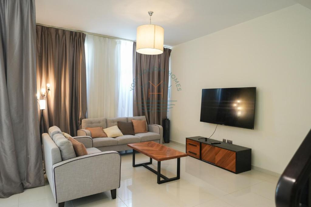 un salon avec un canapé et une télévision dans l'établissement Luxury 4BR Villa with Private Garden, à Dubaï