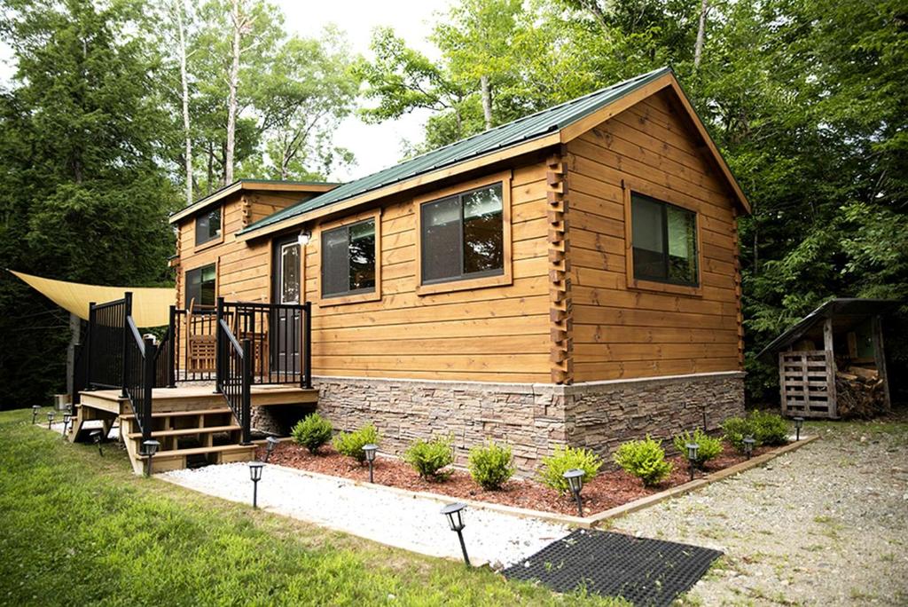 a log cabin with a porch and a deck at Incredible Modern Tiny Log Cabin near the Ammonoosuc River for a Romantic Getaway in New Hampshire in Jericho