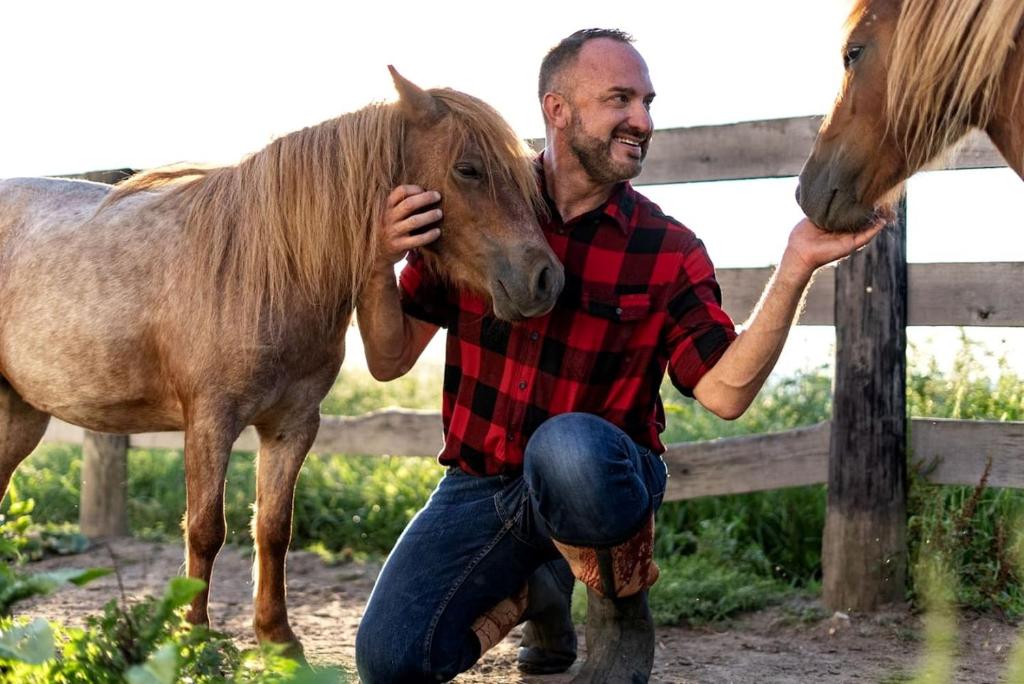 a man is holding a brown horse next to a fence at Cute Cottage on Working Farm for Farmstay Glamping Getaways to Virginia - Perfect for Animal Lovers in Fairview