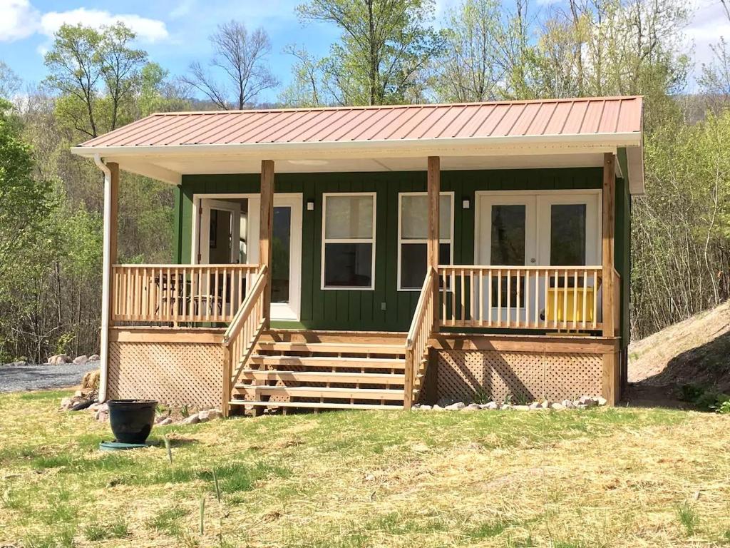 una casetta verde con portico e ponte di Cozy Cabin in the Idyllic Blue Ridge Mountains, Virginia a Konnarock