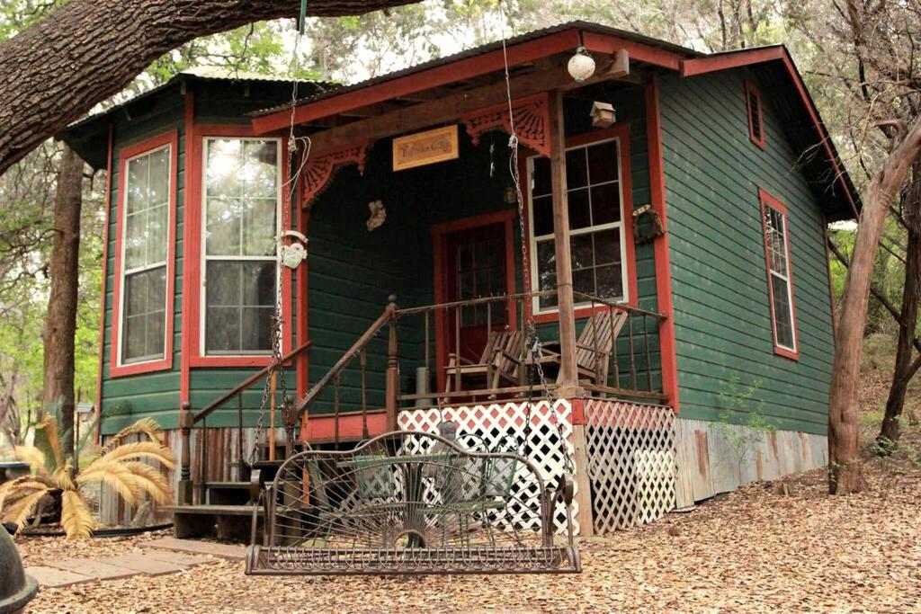 ein grün-rotes Haus mit einer Veranda in der Unterkunft Rustic Victorian-Style Cottage Rental with Clawfoot Bathtub on Hamilton Creek, Texas in Marble Falls