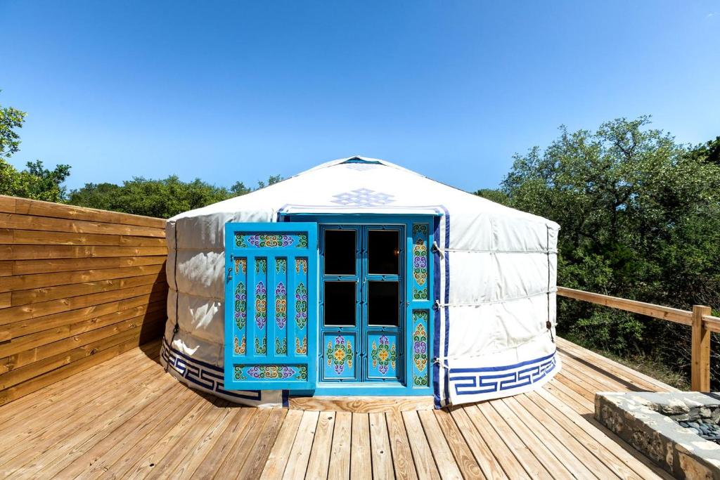Hammetts CrossingにあるPeaceful Couples Yurt with Hot Tub in Dripping Springs, Texasのデッキに青い扉が付いたパオ