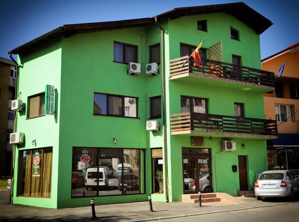 a green building with a balcony and a flag at Pensiunea Caramida Verde in Craiova
