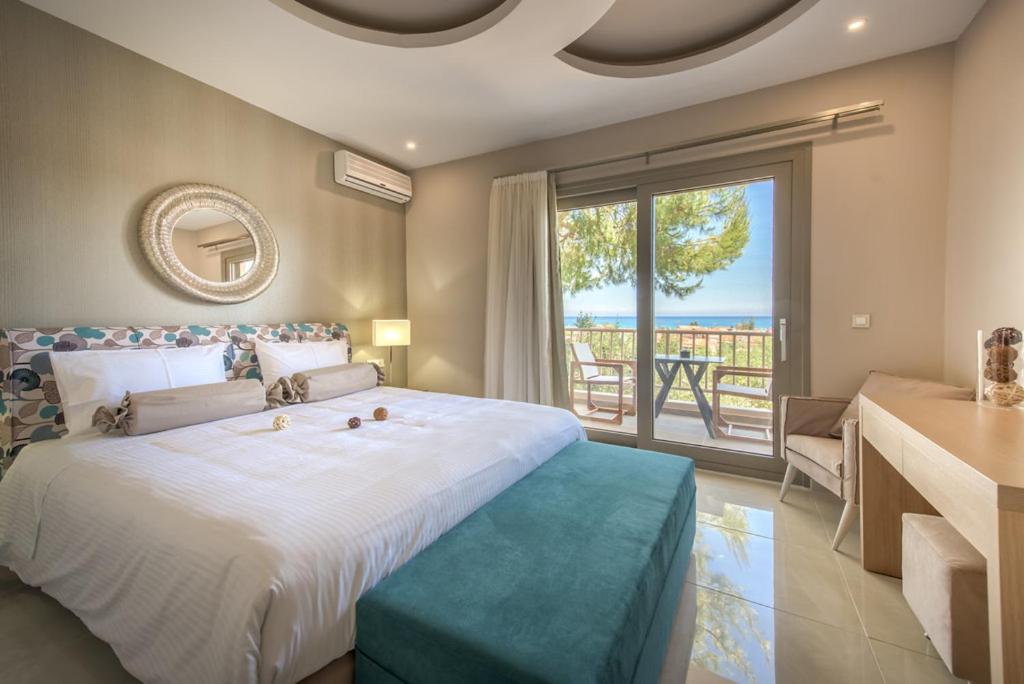a bedroom with a large bed and a large window at Koukounaria Hotel & Suites in Alykes