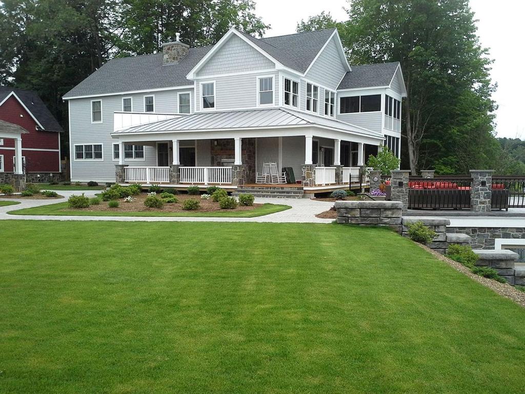 a large white house with a lawn in front of it at Four-Bedroom Luxury House Rental on Pontoosuc Lake in the Berkshires in Lanesborough