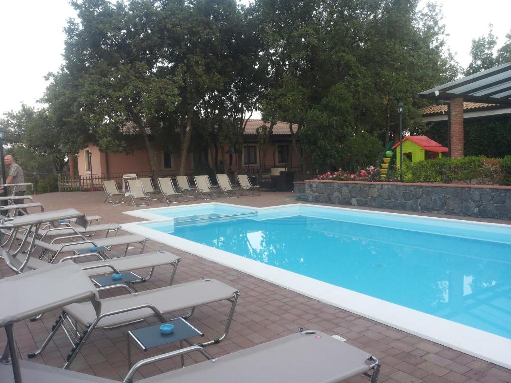 a swimming pool with chairs and a table and a playground at Poggiofelice B&B in Zafferana Etnea