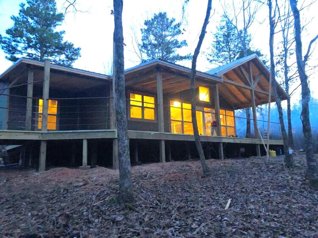 a large wooden house in the middle of trees at Amazing Cabin Rental near Ouachita National Forest for Weekend Getaways in Oklahoma in Hodgen